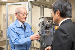 Photo of Dr. Yoshino explaining production process for conventional lithium-ion battery
