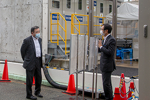 Photo of Minister Kajiyama observing 100% hydrogen-fueled, dry low-NOx gas turbine Text caption: Minister Kajiyama observing 100% hydrogen-fueled, dry low-NOx gas turbine