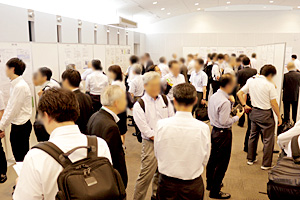 Photo of meeting participants engaged in lively discussions with project implementers at poster session