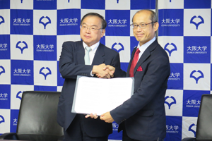 Photo of Executive Director Watanabe and Senior Executive Vice President Kaneda displaying signed MOC