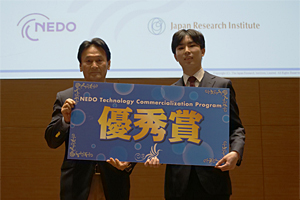 優秀賞を受賞したMicrobialchem（右）と久木田理事（左）の写真