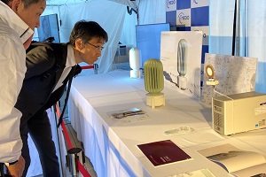 「空気からCO2を回収する技術と社会デザイン」の展示の説明を受けるNEDO西村理事の写真