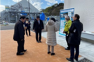 CR拠点・実証研究エリアで開発され、舗装に使用されているコンクリート材の説明を受ける吉田経済産業大臣政務官（右から4人目）とNEDO飯村理事（右から3人目）の写真