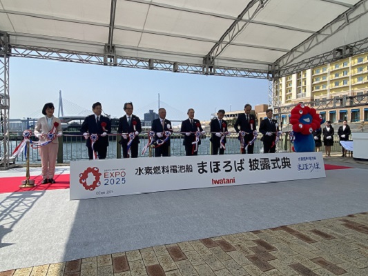 Photo of Dr. Iimura Executive Director of NEDO (far left) and Myaku-Myaku, the official mascot of the Osaka-Kansai Expo (far right), participate in the ribbon-cutting ceremony alongside other attendees.