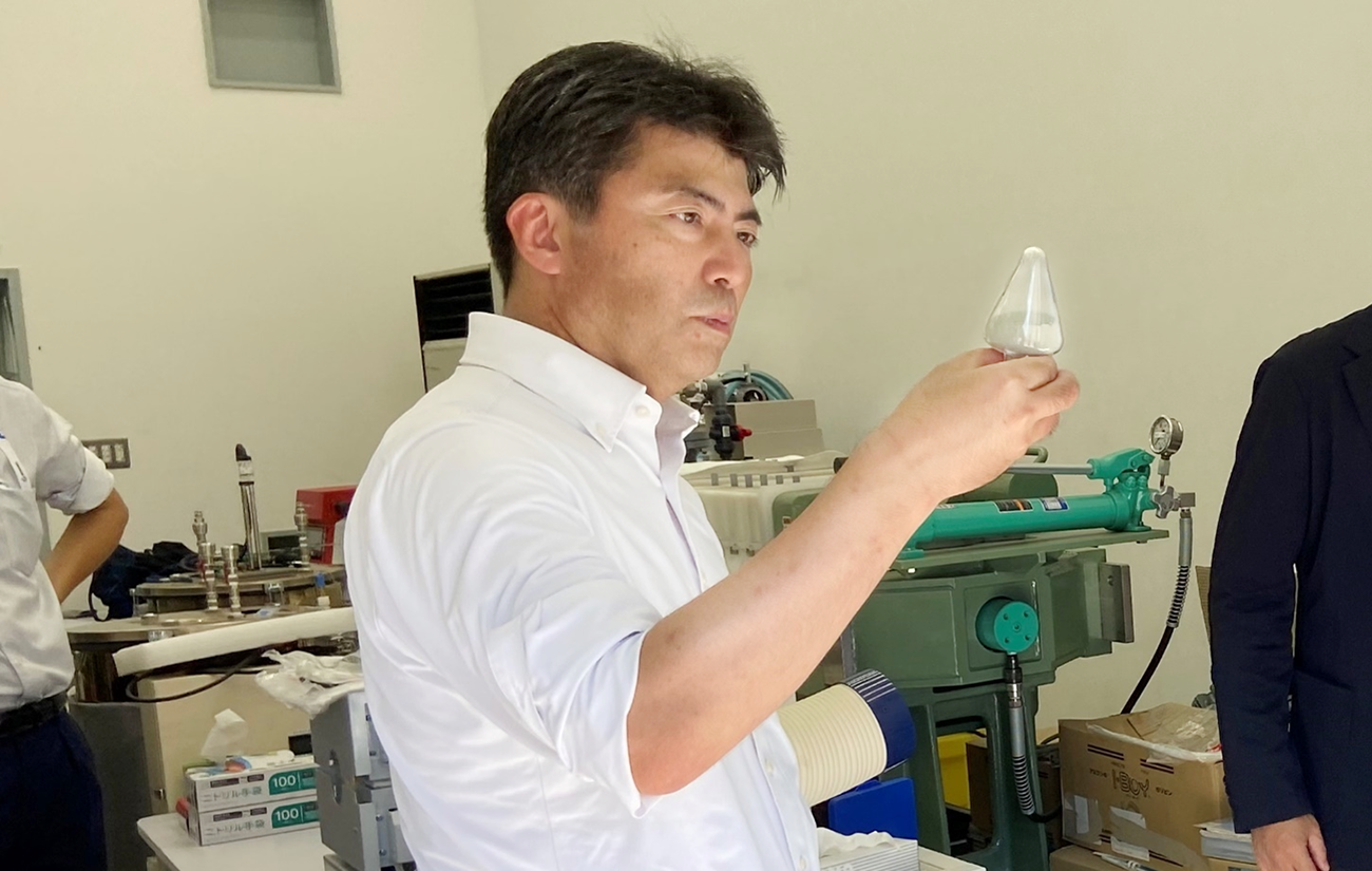 CR拠点の基礎研究エリアで製品サンプルを手に取り確認をする古賀経済産業副大臣の写真