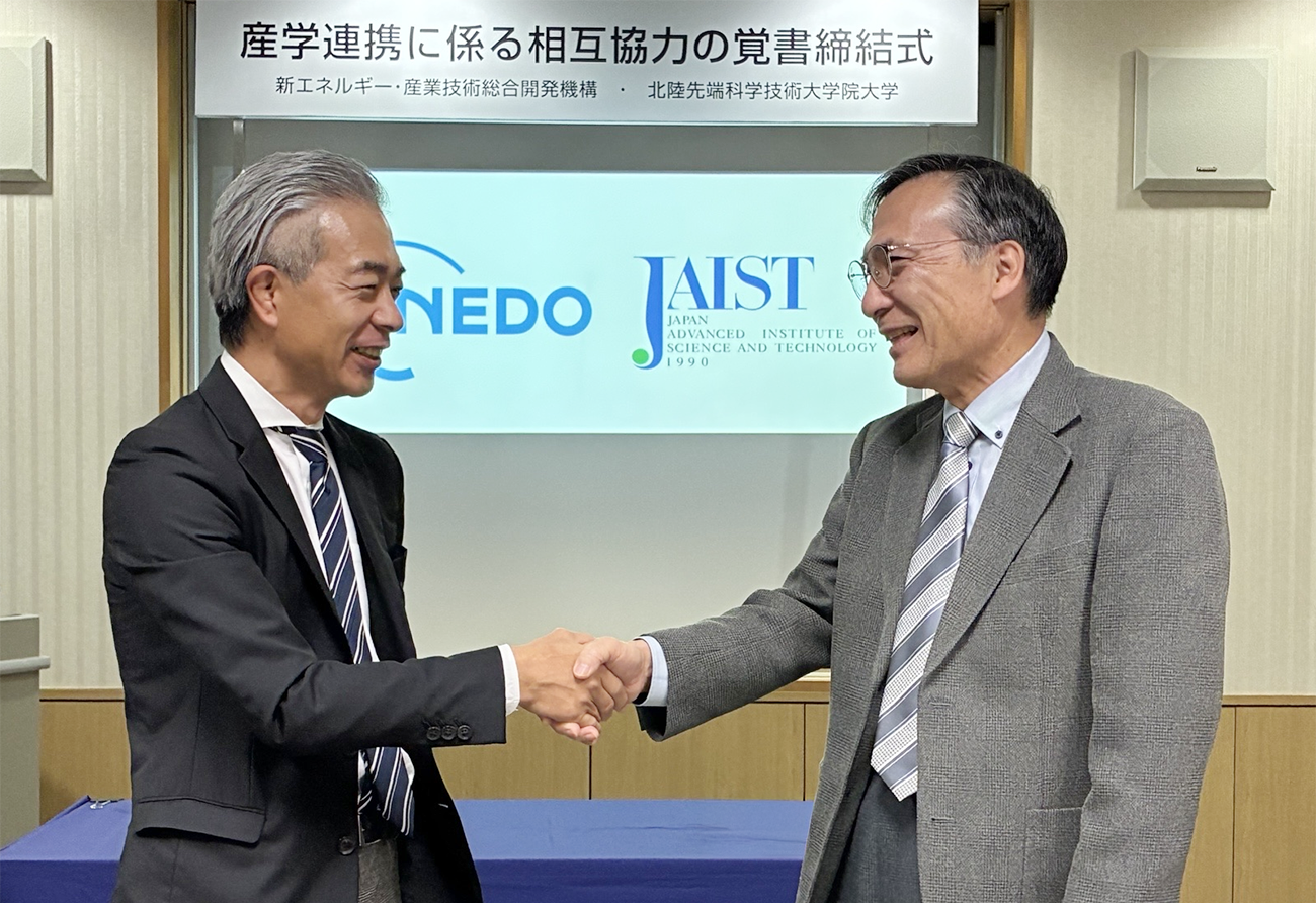 締結後握手を交わす北陸先端科学技術大学院大学寺野学長とネド吉田理事の写真